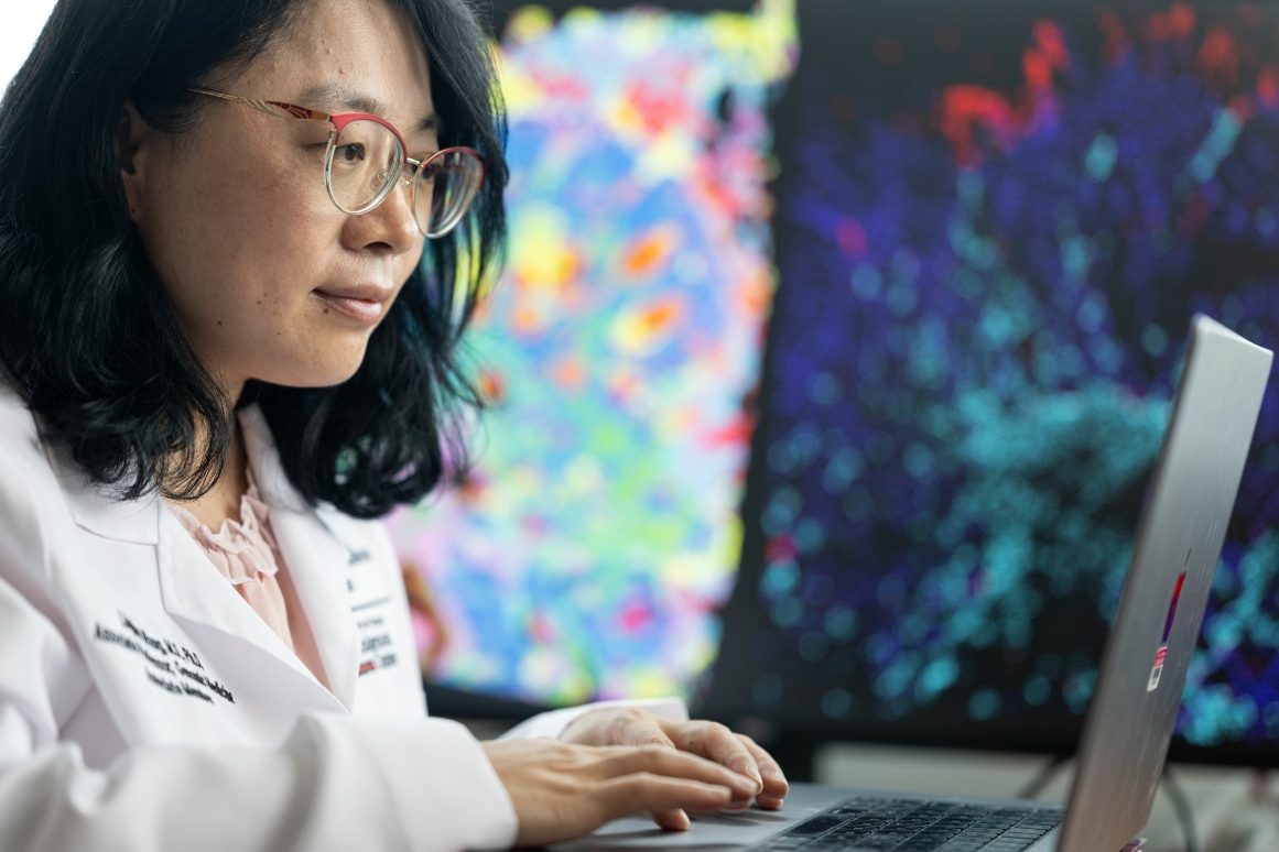 Linghua Wang sits at her desk showcasing an image on her laptop screen 