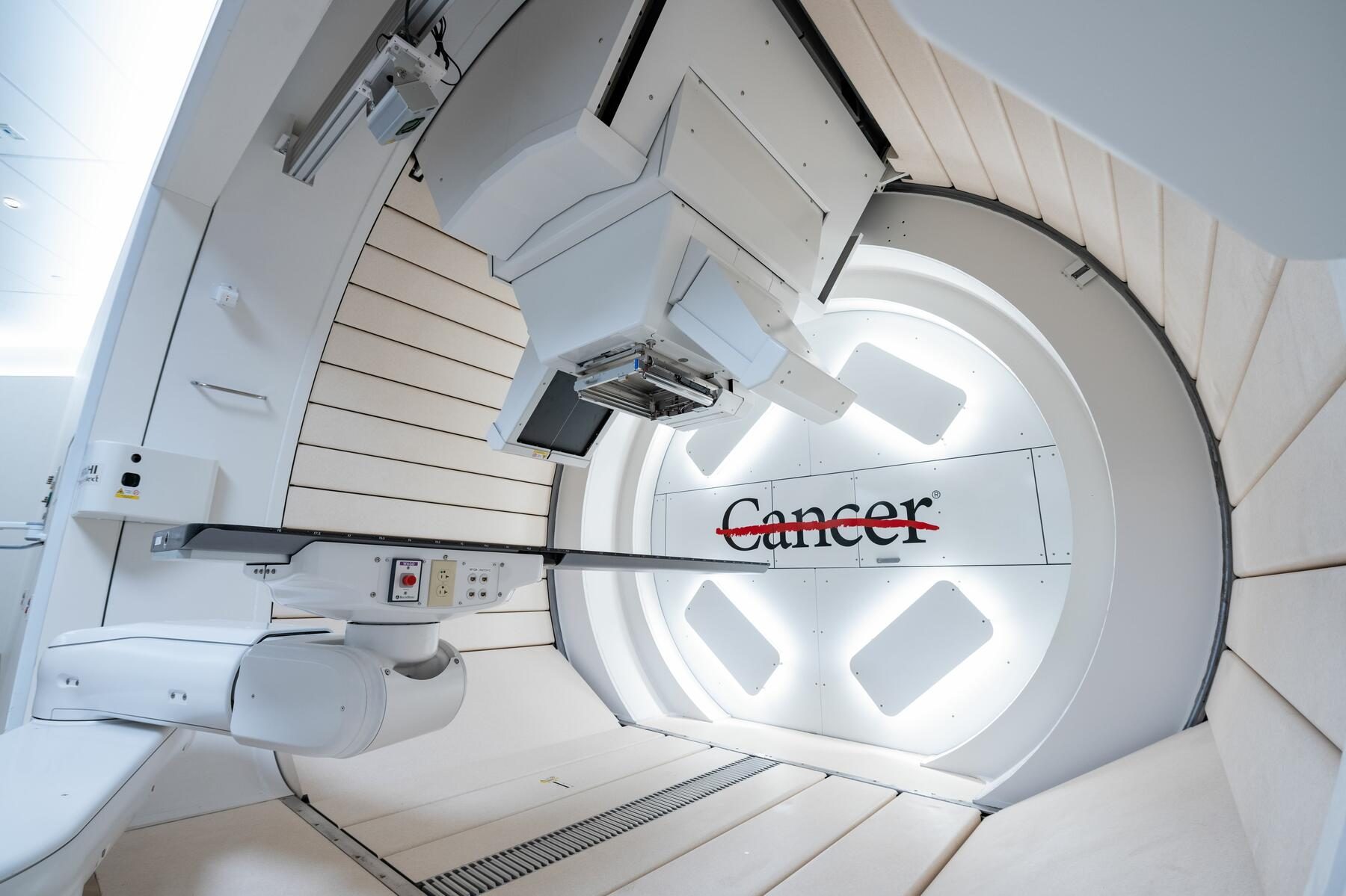 Brightly lit radiation treatment platform in UT MD Anderon's Proton Therapy Center 2 building with UT MD Anderson logo showing