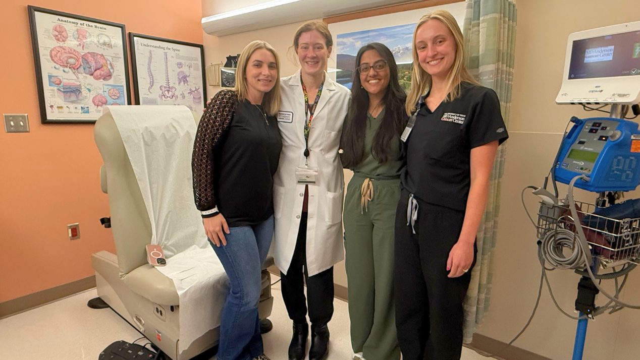 A woman stands next to three medical professionals in a clinic room