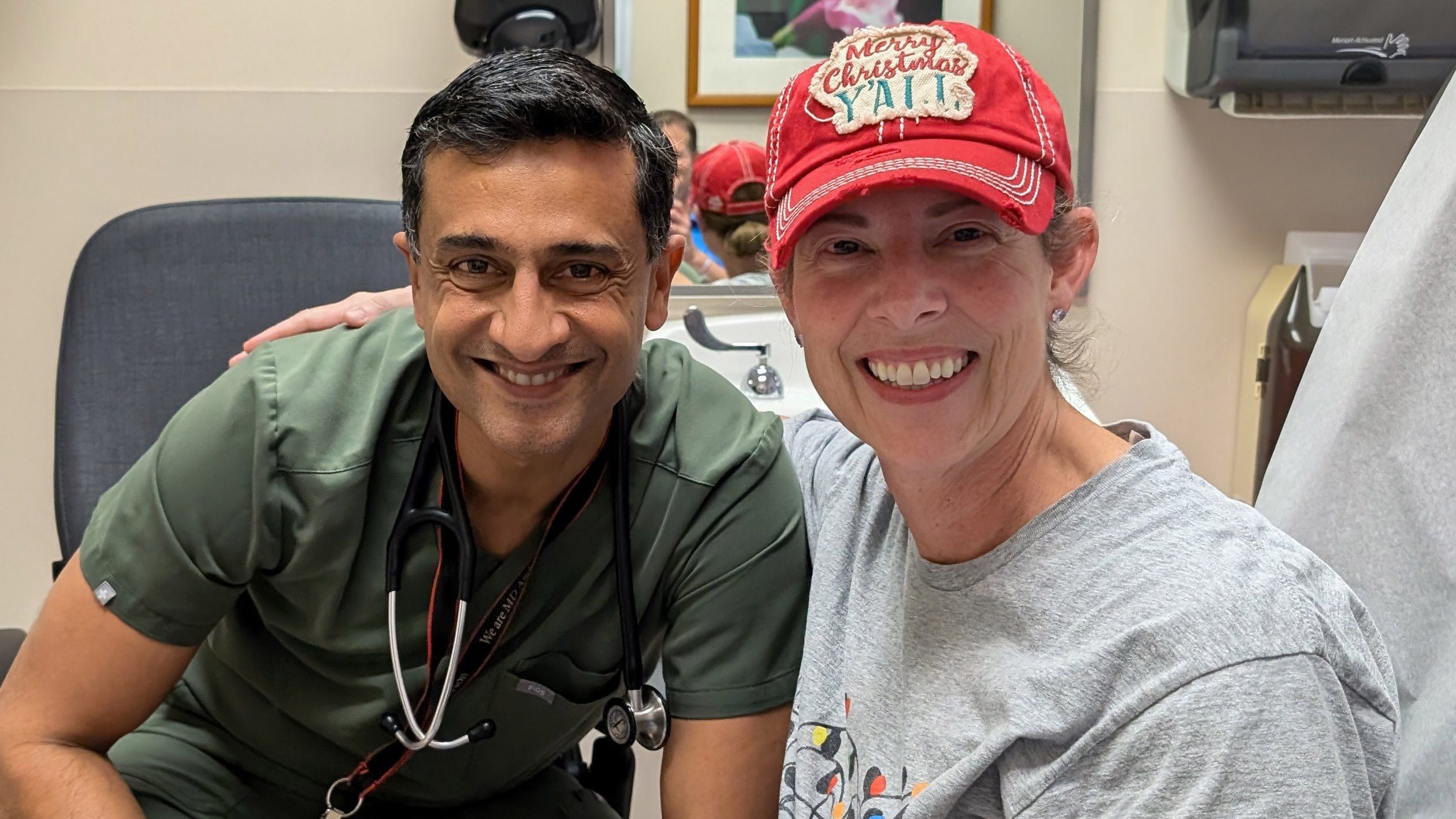 Smiling woman wearing a baseball cap sits next to male doctor