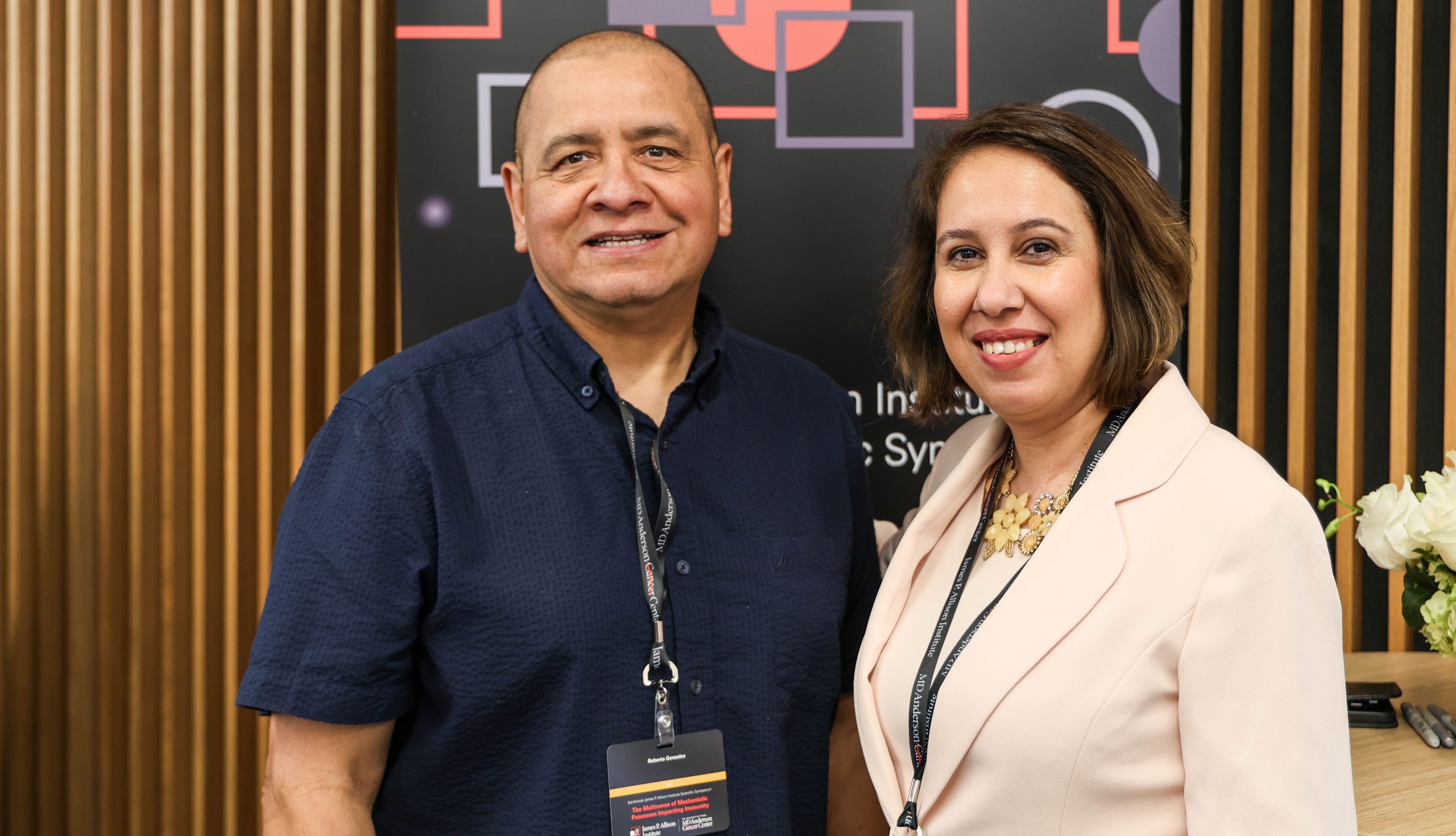 A man and a woman stand next to each other smiling