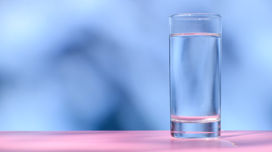 Glass of water sitting on a pink surface