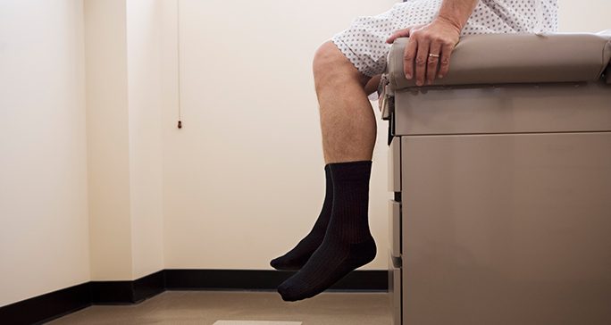 Man sitting in doctor's office with legs hanging off the table