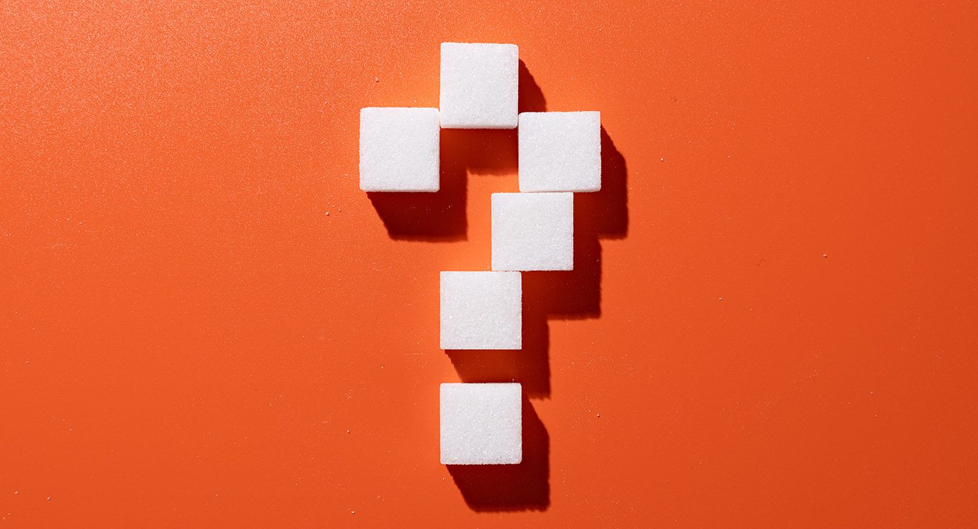 Sugar cubes in the shape of a question mark on an orange background