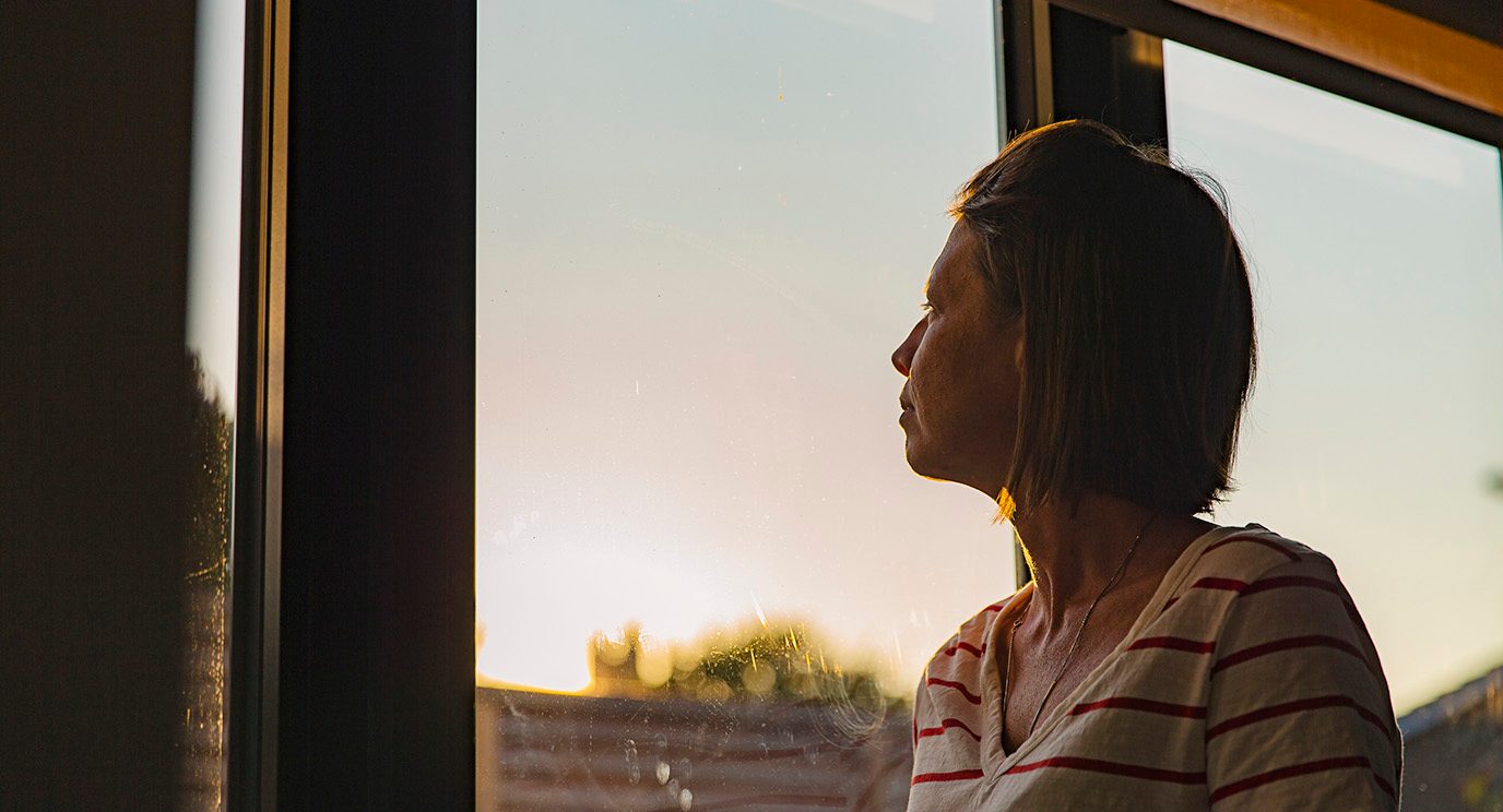 Woman looks out the window with a worried expression on her face