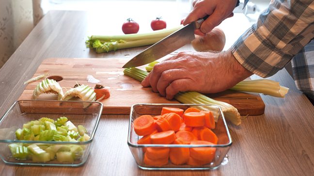 Photo of hands chopping vegetables and putting them into containers.