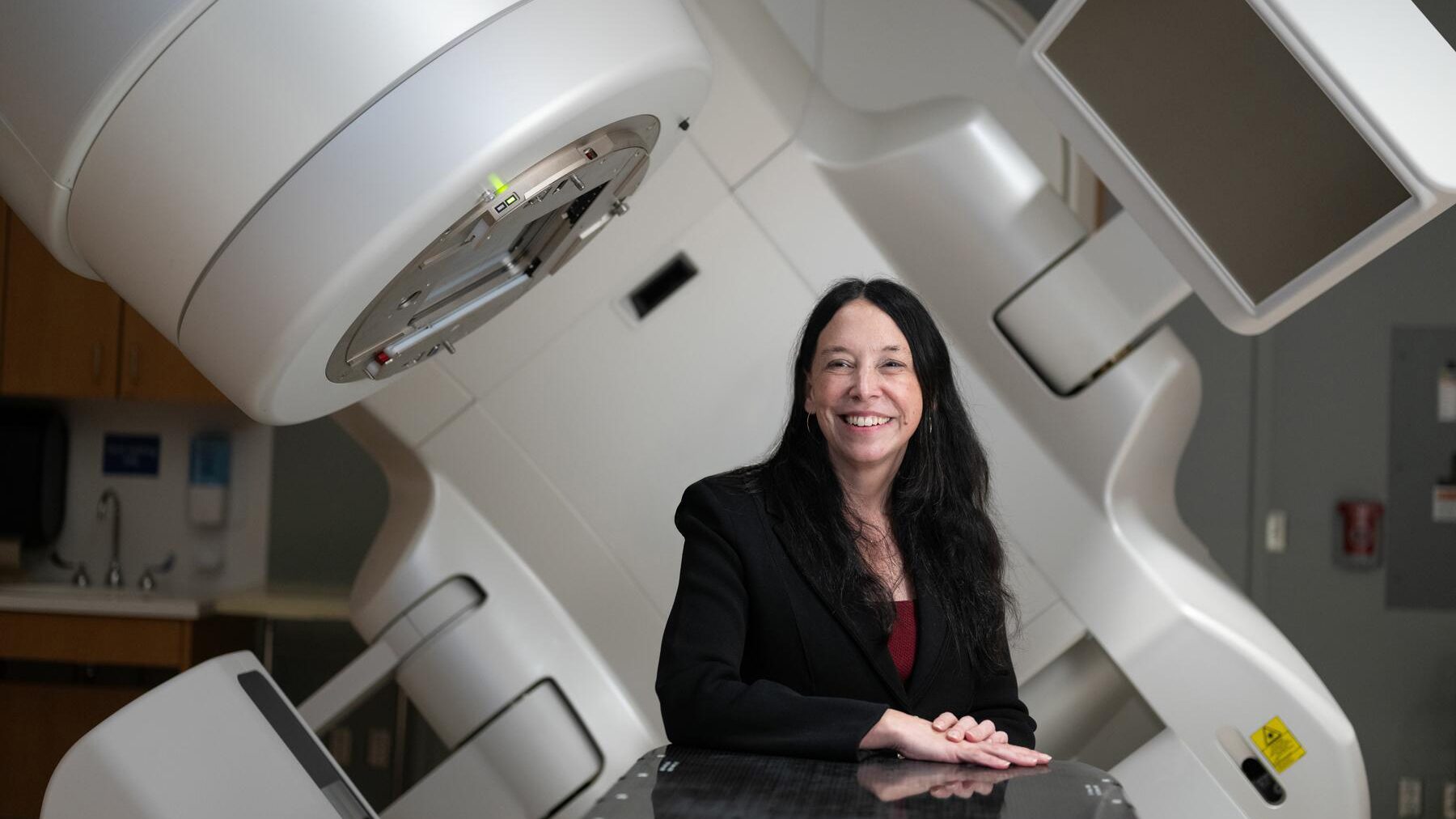 Doctor sits in front of a linear accelerator