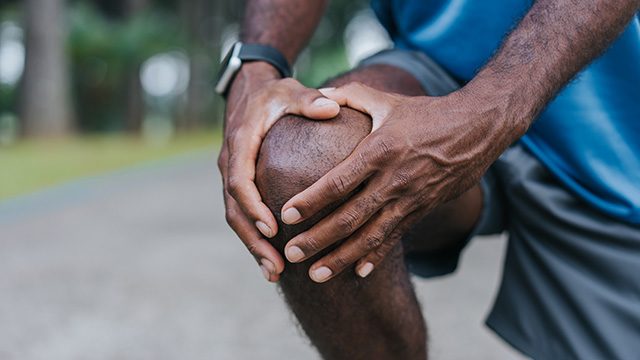 Unidentified man massages his knee while exercising