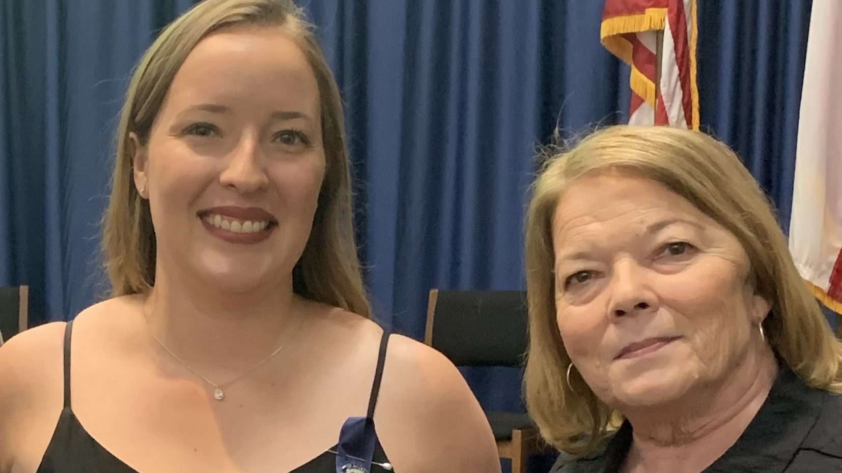 Two women stand side by side smiling
