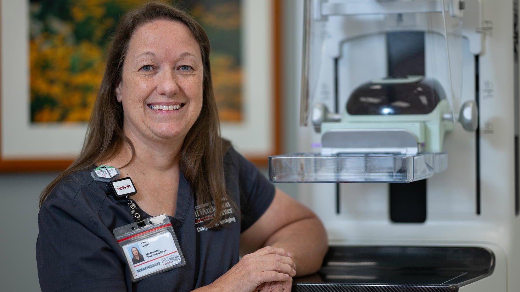 Woman stands with her arms propped onto a mammography machine