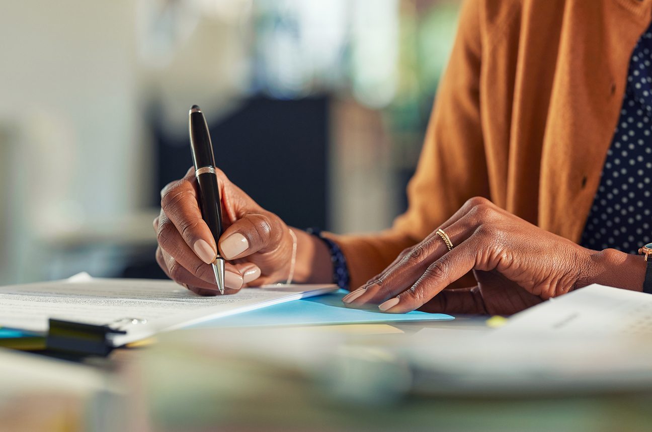 Close-up of a woman's hands as she signs paperwork