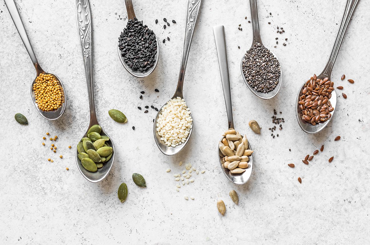 Artistic arrangement of 7 metal spoons filled with different seeds 