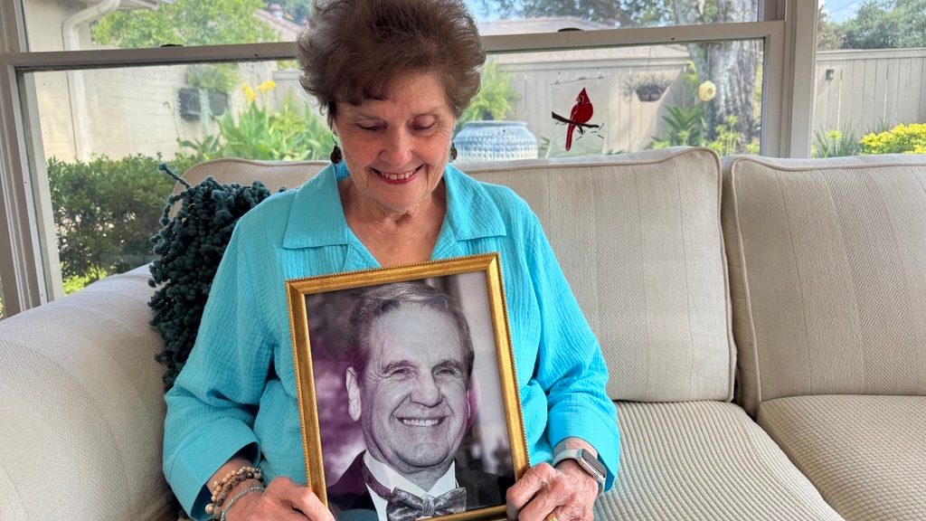 Woman holds a framed picture of a man