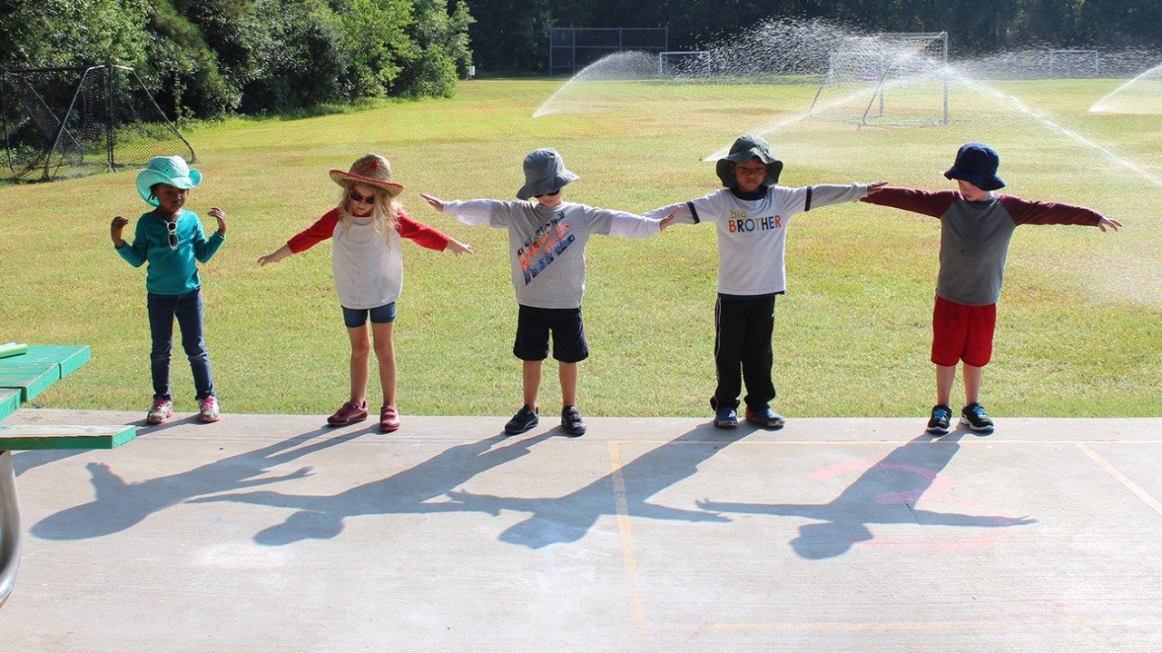 children outside measuring shadows