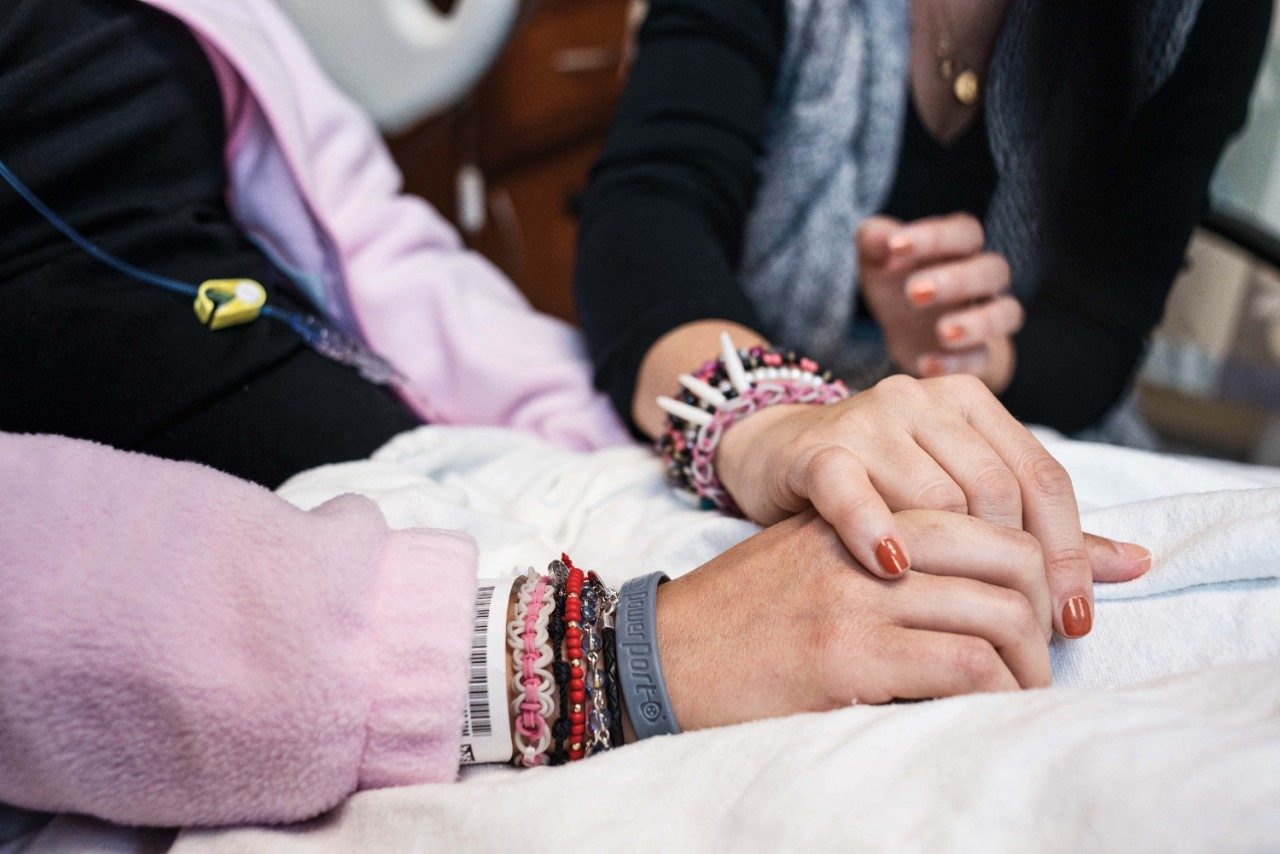 Close-up photo of someone holding a patient's hands