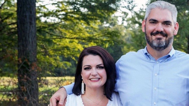 Siblings Lindsay Cassidy and Christopher Welch smiling outdoors among the trees.