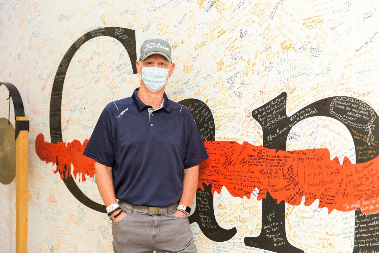 Chuck Williams stands near the gong at MD Anderson Proton Therapy Center after completing testicular cancer treatment.