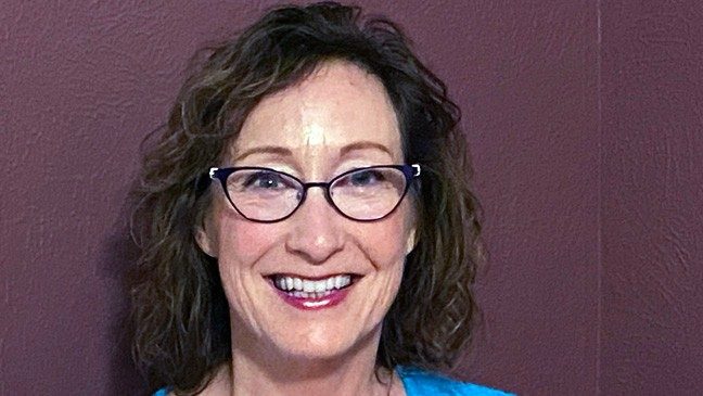 Portrait of Pam Blaine smiling against purple background