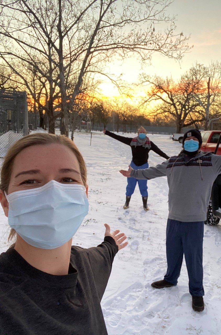 Three staff members in face masks stand outside in the snow