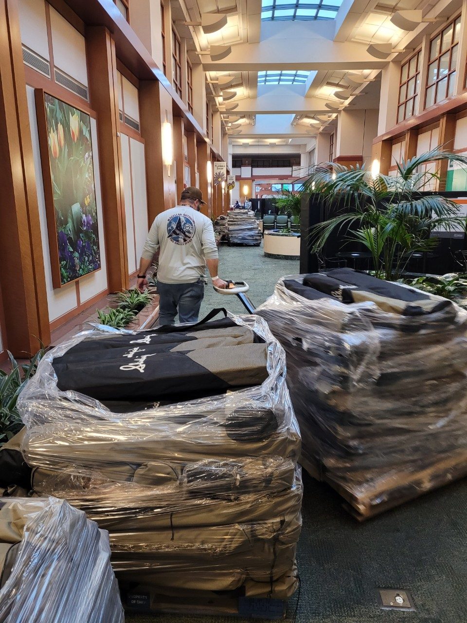 Man pulls two carts containing black cots through an MD Anderson hallway