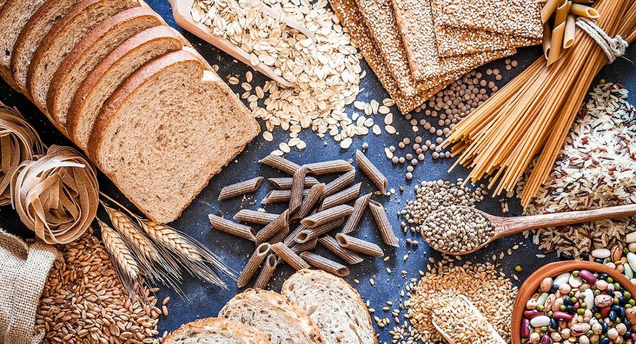 Top view of wholegrain and cereal composition shot on rustic wooden table. This type of food is rich of fiber and is ideal for dieting. The composition includes wholegrain sliced bread, wholegrain pasta, oat flakes, flax seed, brown rice, mixed beans, wholegrain crackers and spelt. Predominant color is brown. DSRL studio photo taken with Canon EOS 5D Mk II and Canon EF 100mm f/2.8L Macro IS USM