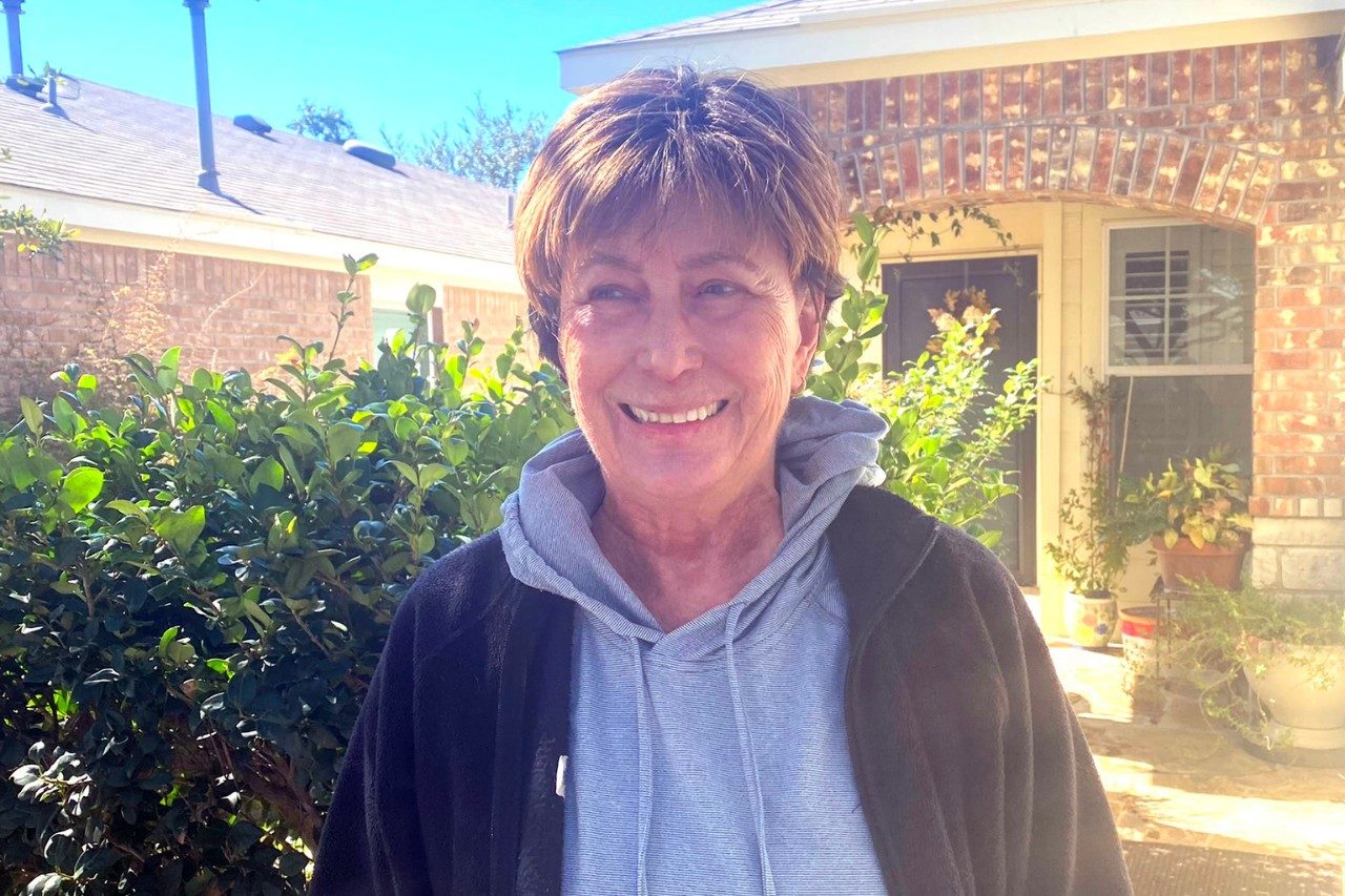 Evelyn Saunders Webb standing outside in front of a house.