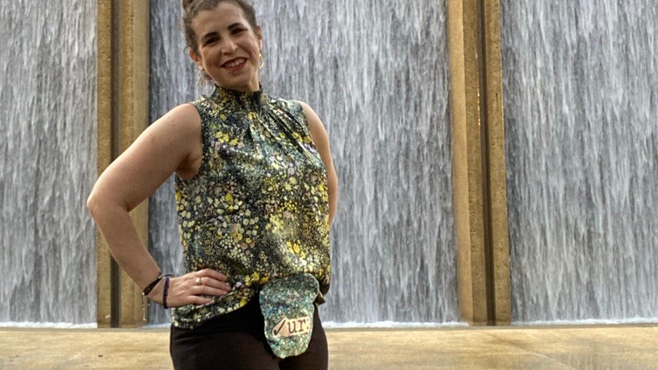 Colorectal cancer survivor Allison Rosen stands with hands on her hips in front of a water wall