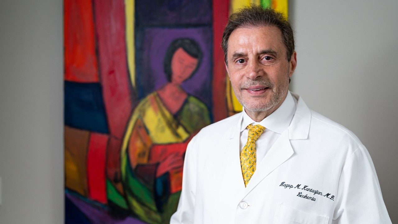Leukemia specialist Hagop Kantarjian, M.D., poses with one of his favorite paintings, "Seated Woman with Red Guitar" (2021). 