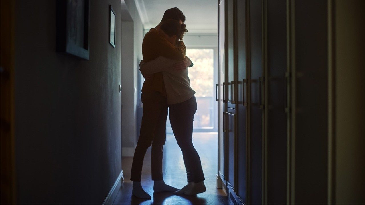 Silhouettes of a man and woman embracing in a dark hallway