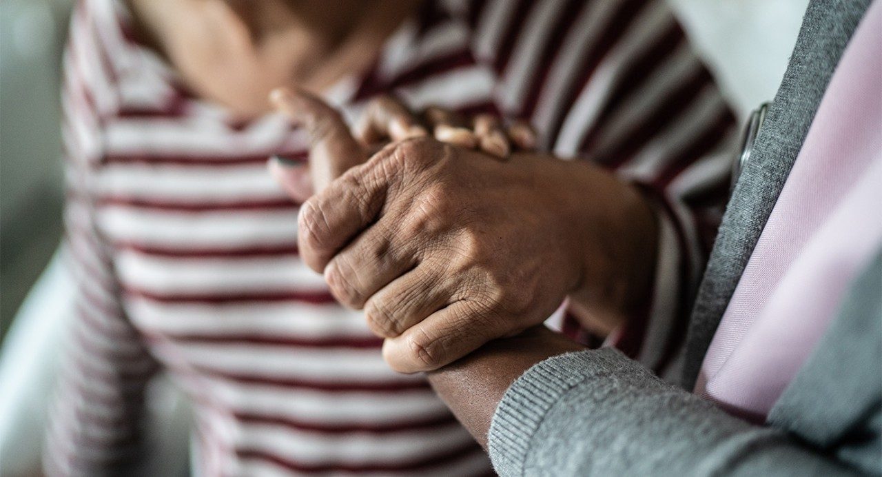 Close-up view of hands clasped together in a gesture of emotional support