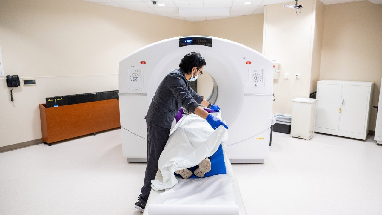 Technologist prepares patient to enter PET scan machine