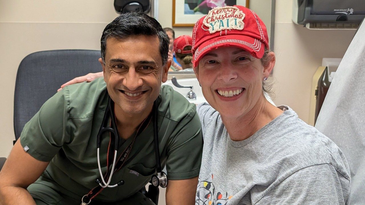 Smiling woman wearing a baseball cap sits next to male doctor