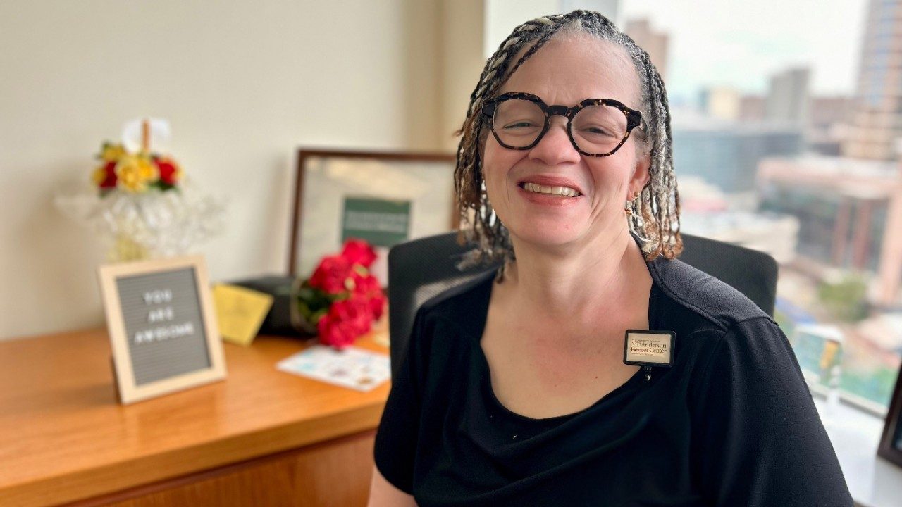 Woman sits in her office smiling