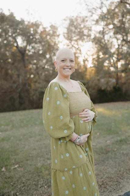 Woman wearing a green dress holds her belly