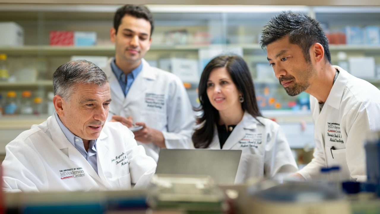 Dr. Heymach and 3 colleagues gathered around a computer on a lab bench