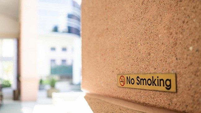 Gold sign reading 'No Smoking' on a limestone wall