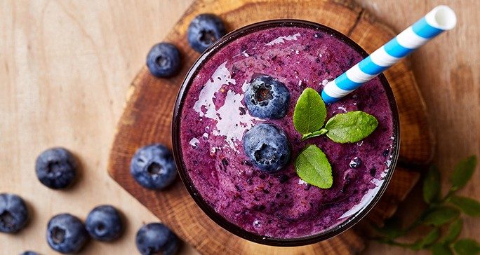 Birds-eye view of delicious blueberry smoothie garnished with fresh mint leaves and berries