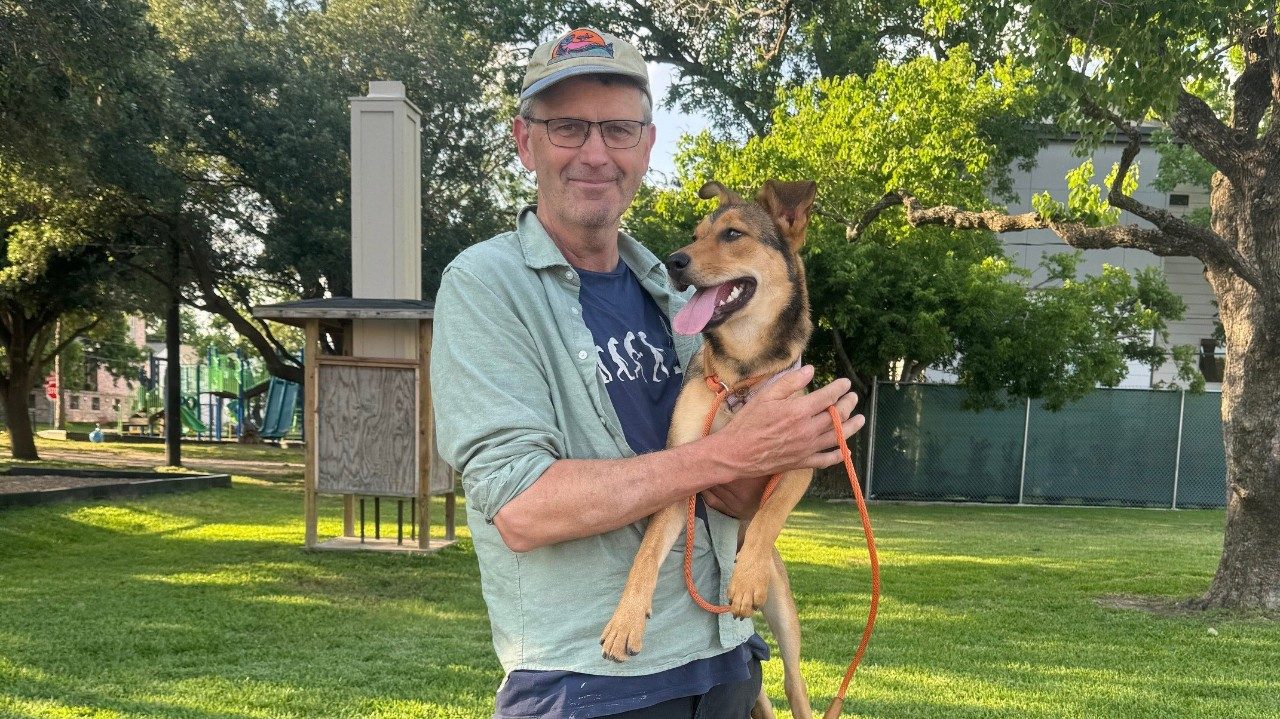 Man holding a tan dog