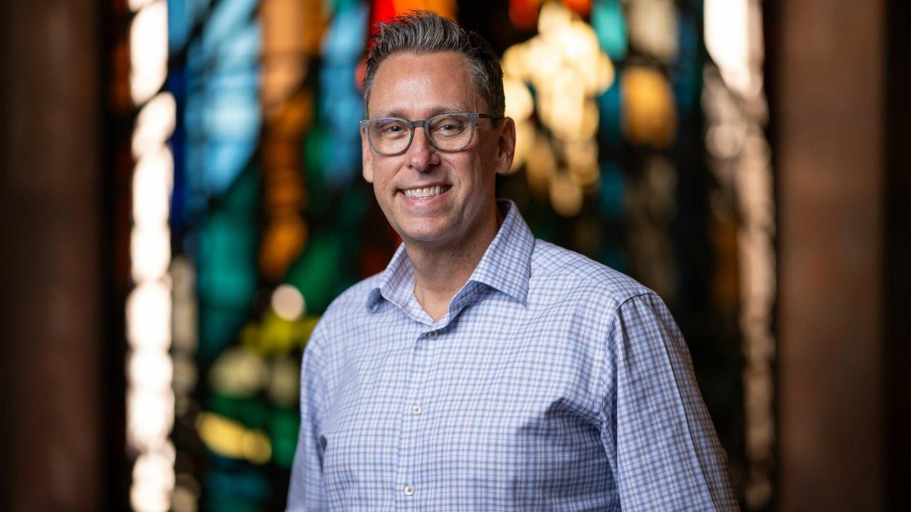 Man stands in front of stained glass