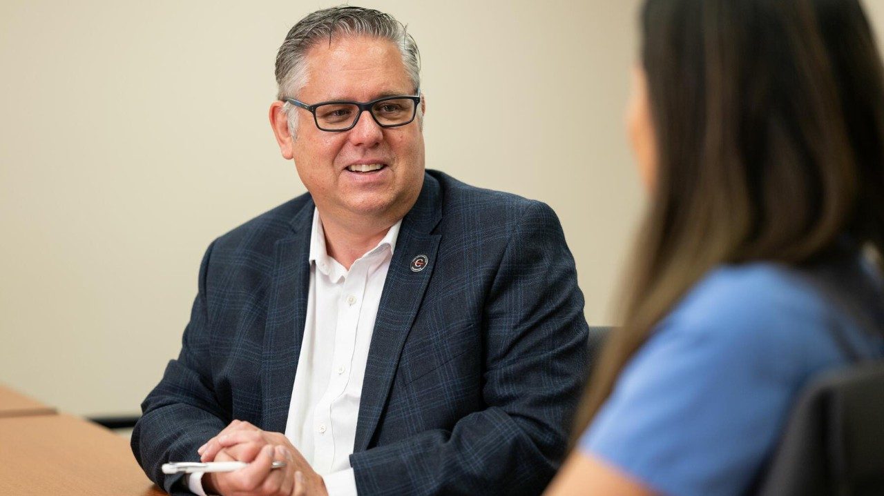 Man sits at a table talking to a nurse