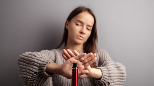 young woman rejecting a vape that is being offered her, and pushing back against the so-called benefits of nicotine