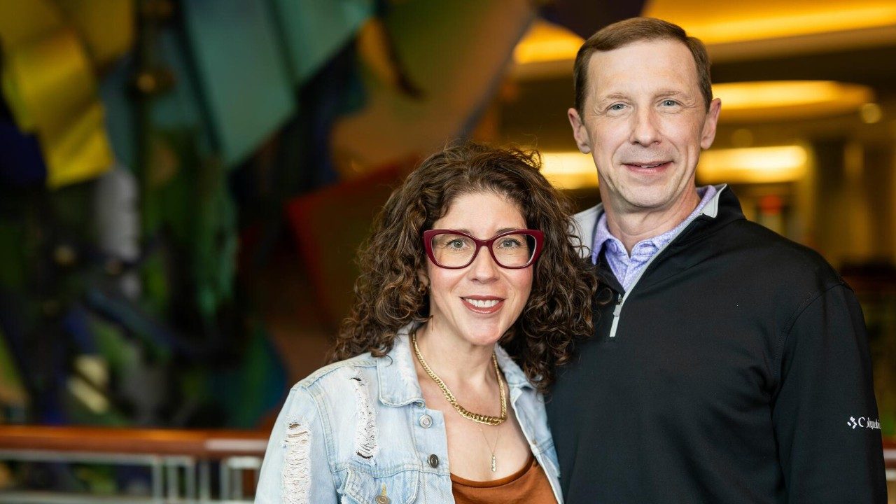 A smiling man and woman stand next to each other