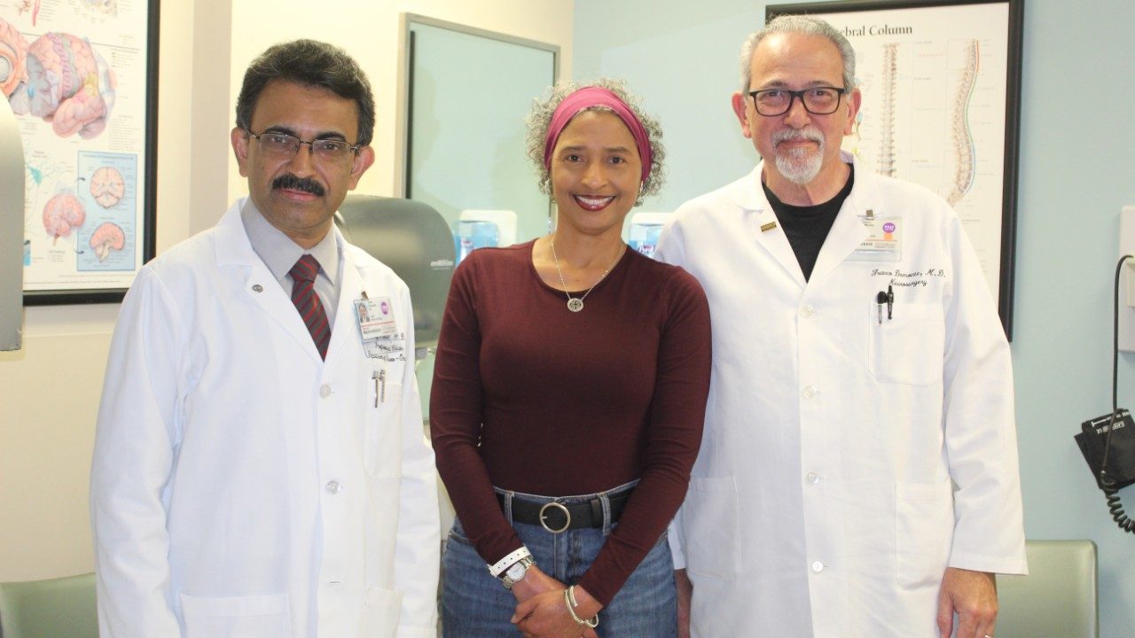 Woman stands in between two male doctors in white coats