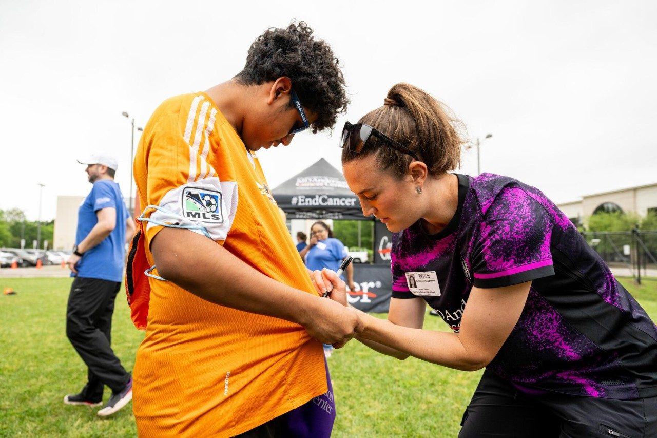 Houston Dash defender Katie Lind signs a Houston Dynamo FC jersey work by a student at Kick Tobacco and Vaping day.
