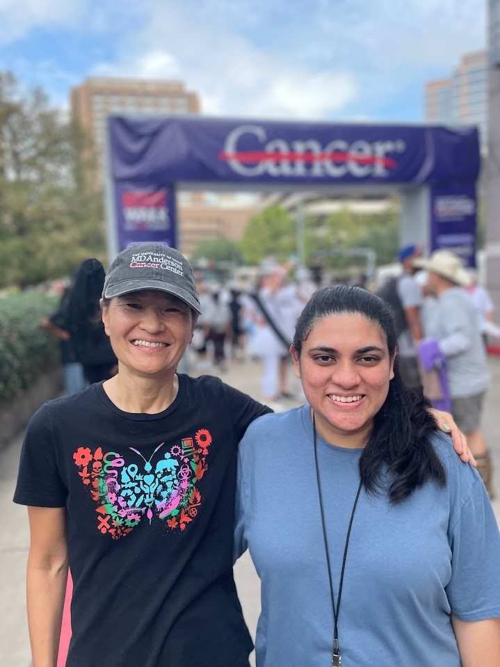 a photo of two people at the Boot Walk to End Cancer with the cancer strikethrough logo visible in the background