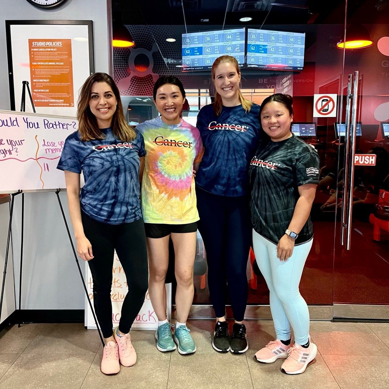A group of fellows posing at a gym while wear MD Anderson shirts with the strikethrough logo visible