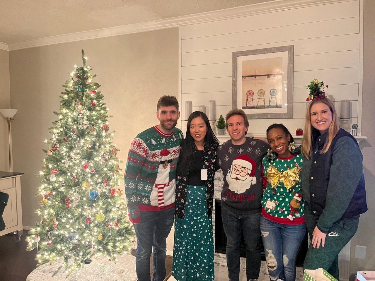 Third-Year Fellows posing for a group photo while wearing holiday attire with a Christmas tree visible next to them