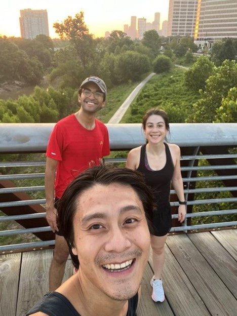Hematology Oncology Fellows posing for a photo while running over a bridge with the city skyline visible behind them