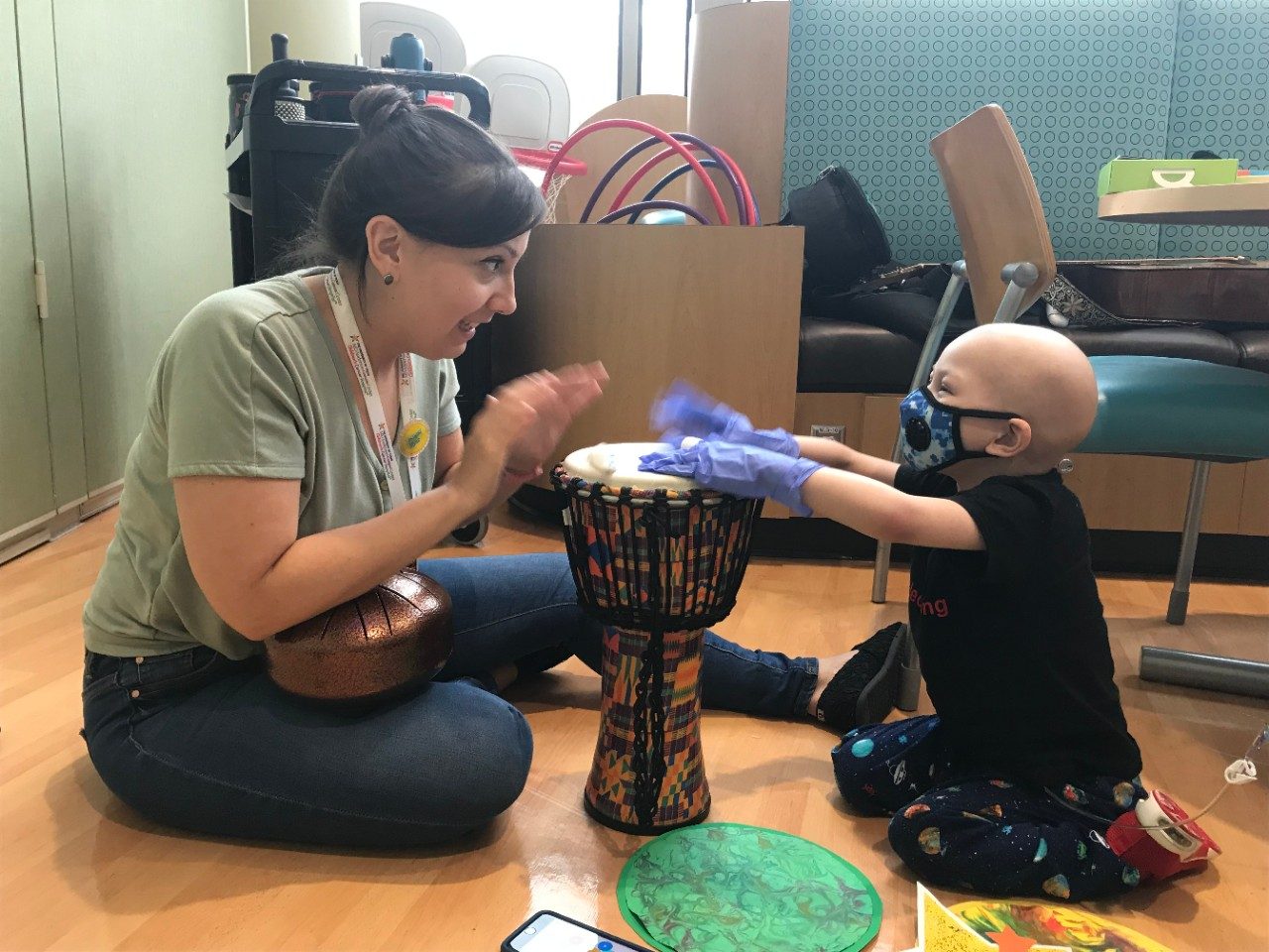 Lady plays drum with pediatric patient