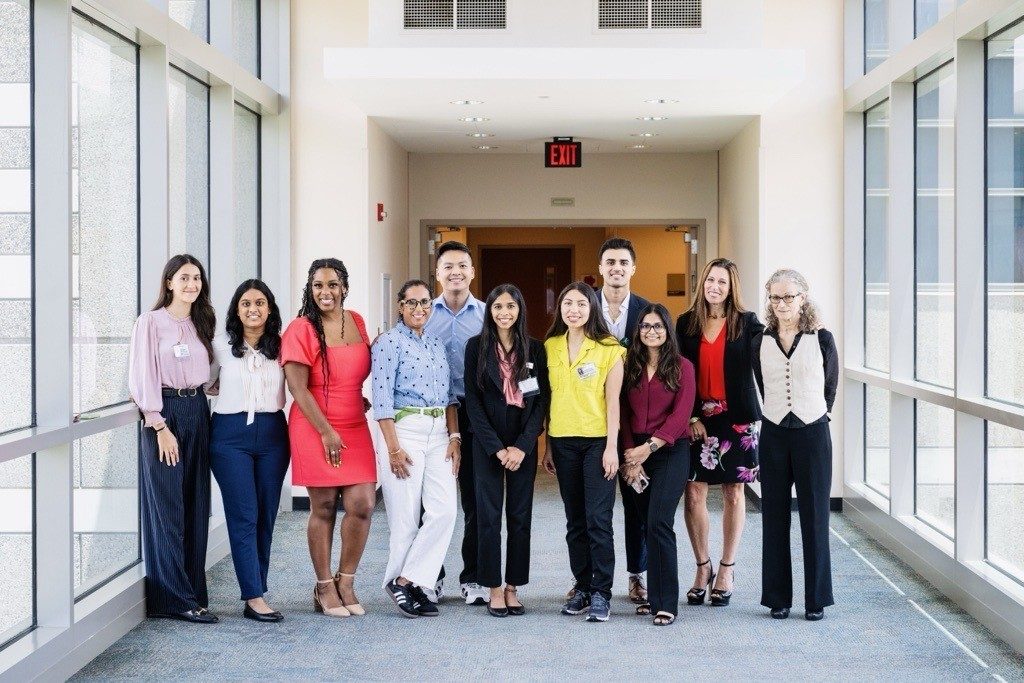 a group of people posing for a photo while standing in a hallway with windows on the side